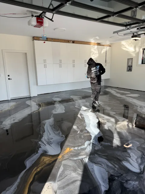 Go2Epoxy installer in company uniform inspecting a newly installed metallic epoxy garage floor